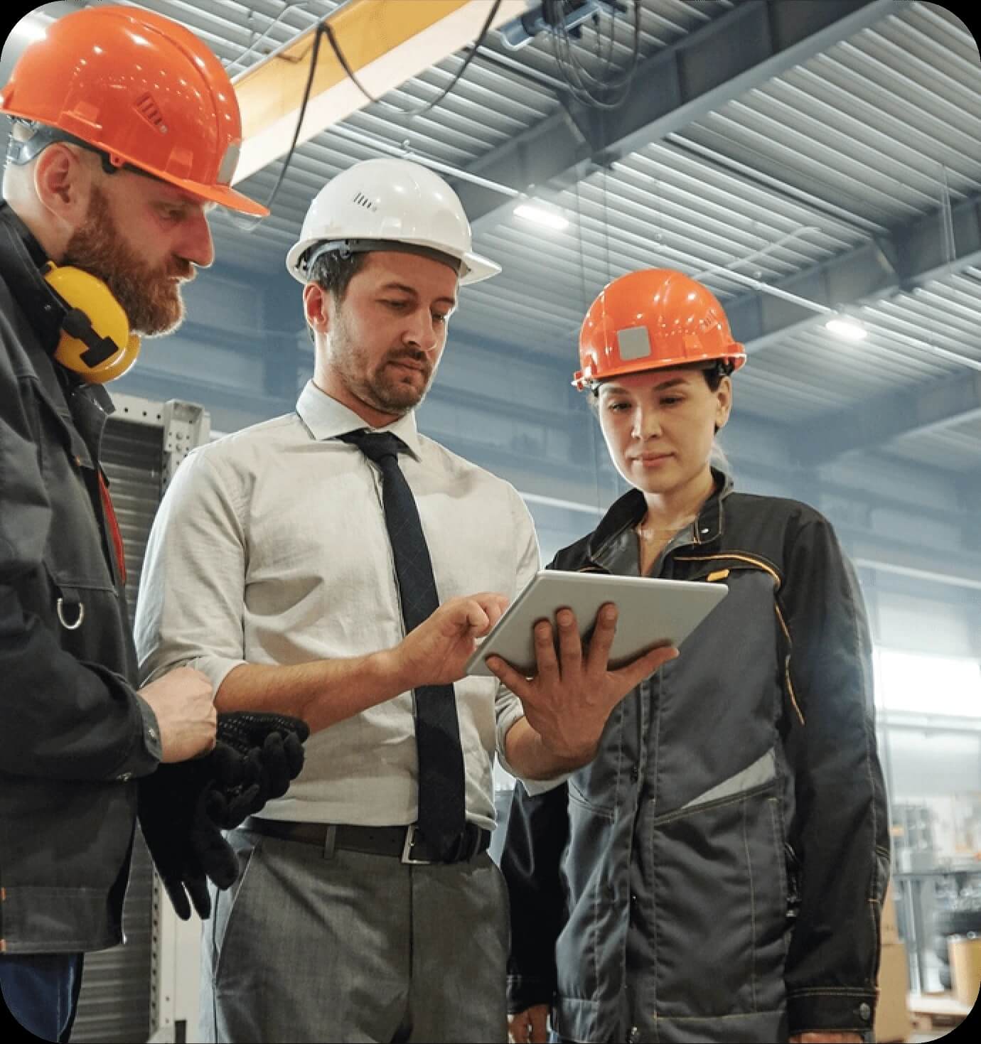 Drei Personen stehen in einer Produktionshalle oder im Bereich der technischen Abläufe. Zwei von ihnen tragen orange Helme und Arbeitskleidung, die dritte – in einem weißen Hemd und mit Krawatte – sticht als Manager oder externer Experte hervor. Alle blicken aufmerksam auf das Tablet, das der Mann in der Mitte hält – es ist ein Moment der digitalen Koordination zwischen Führung und technischem Personal.
